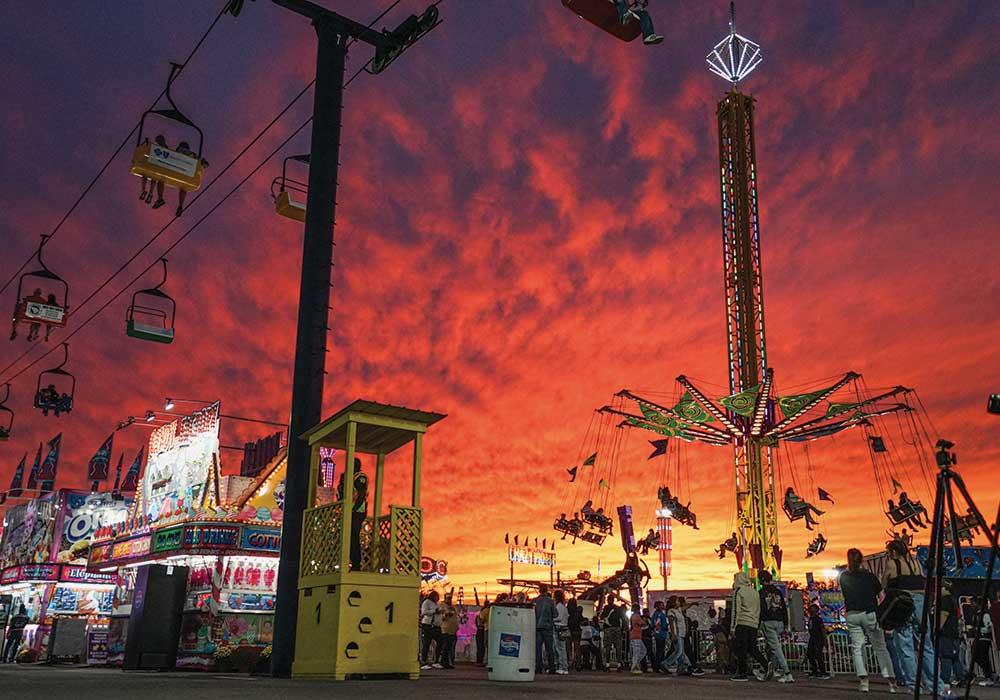 A sunset at the SC State Fair with the swings ride in the foreground.