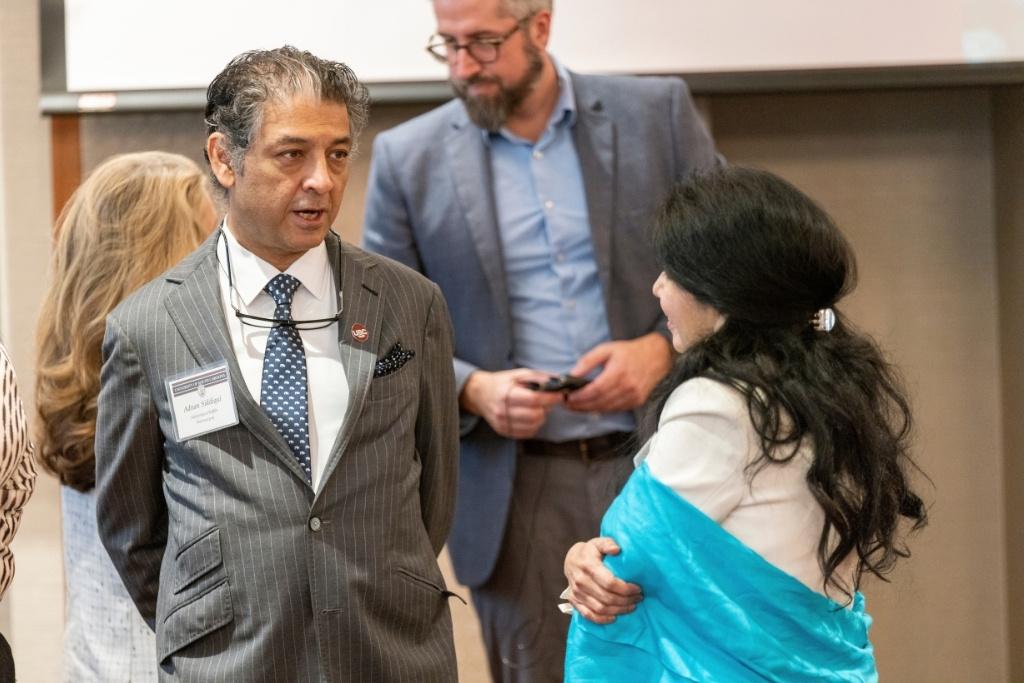Two people in professional clothing speak after a presentation