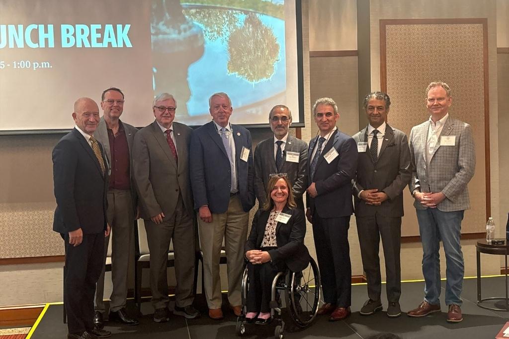 Nine people pose for a group photo on the stage of the Brain Health Symposium at USC's Alumni Center.