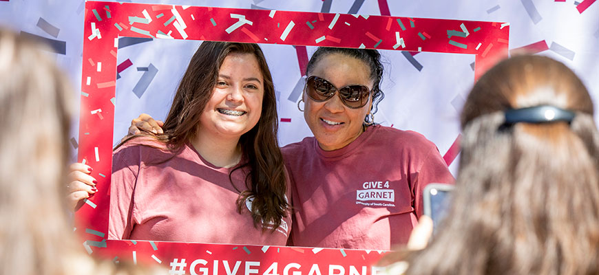 Dawn Staley poses behind a cutout frame with a fan on Greene Street during the 2019 Give 4 Garnet event.