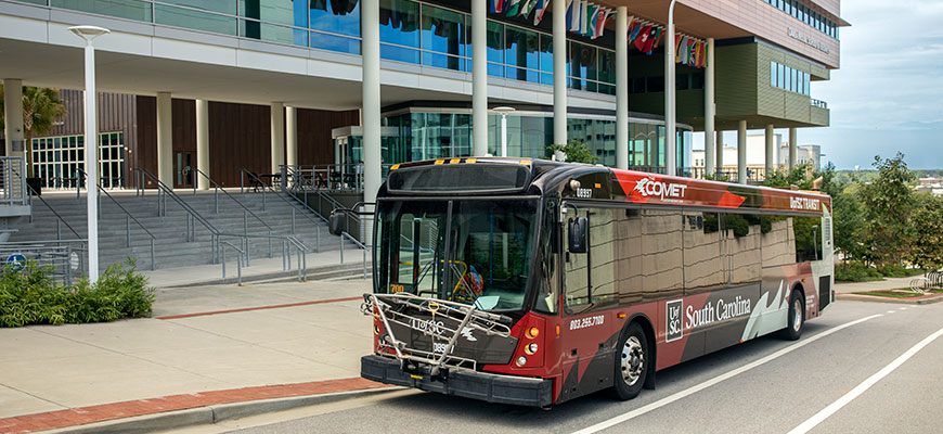The new COMET/UofSC Transit branded bus in front of the Darla Moore School of Business