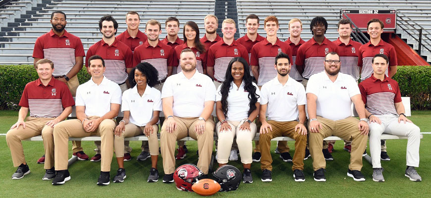 Kjahna O and Gamecock football colleagues pose for a group photo on the field