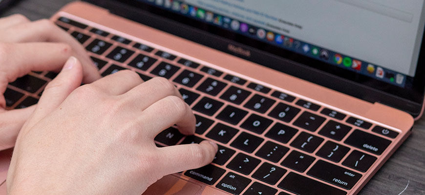 A set of hands hovers over a Macbook keyboard