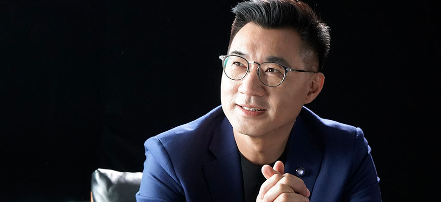 Johnny Chiang looking up, wearing glasses and blue sports jacket