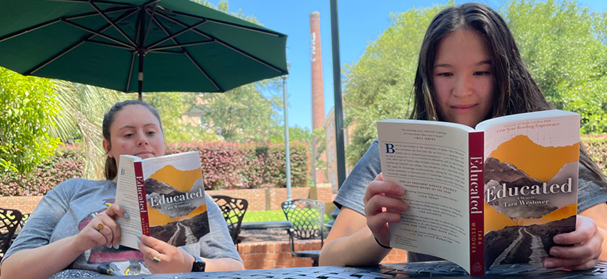 Two students read Educated, showing Brooke Daniels' cover design.