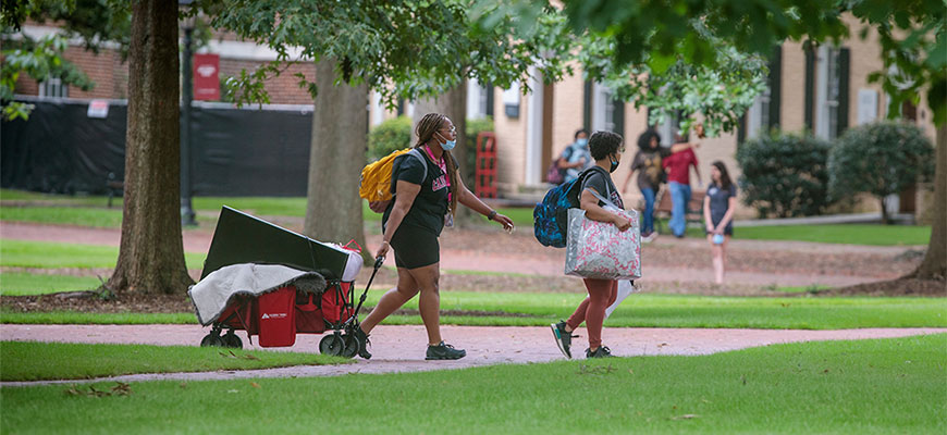 Two people walk their cart across the Horseshoe during move-in 2021