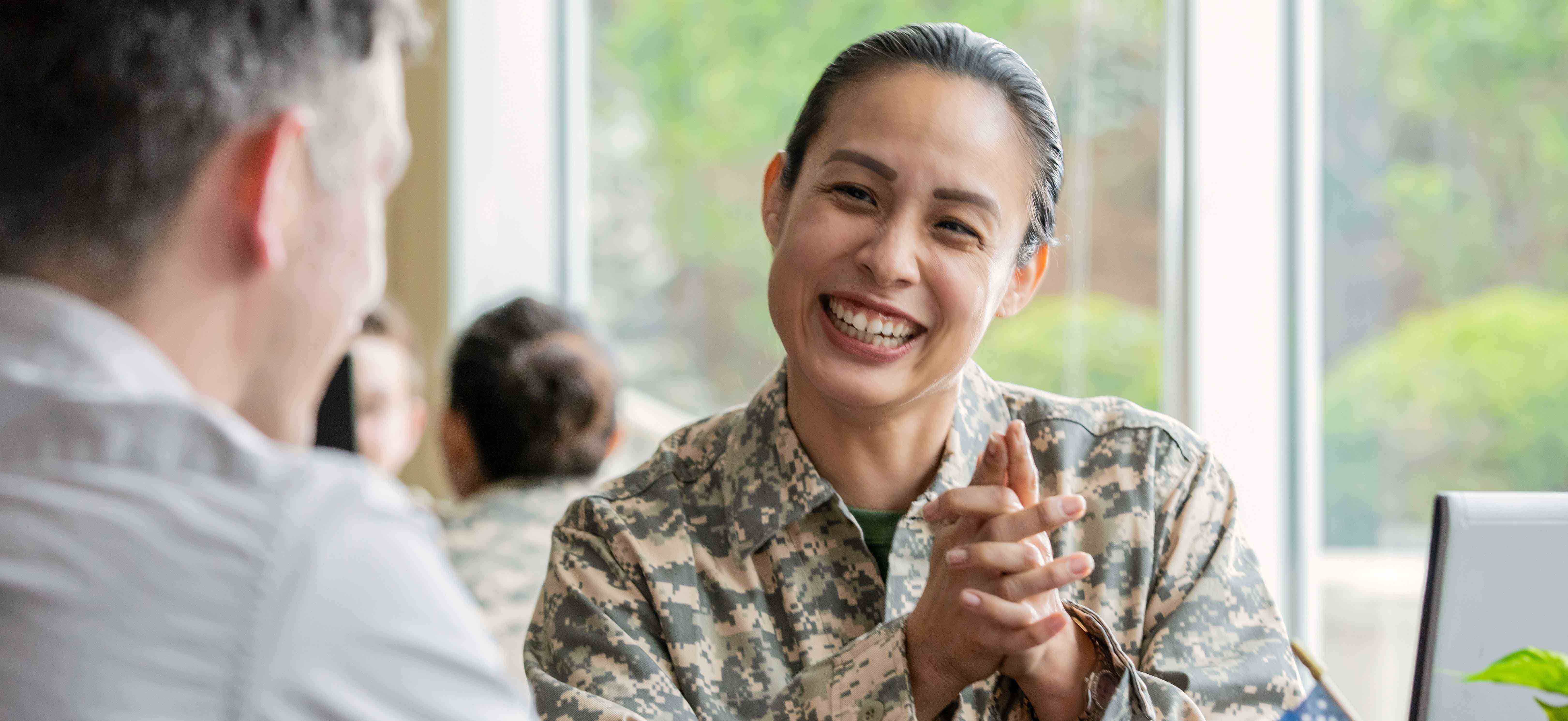 Female veteran in in uniform sitting at a table smiling