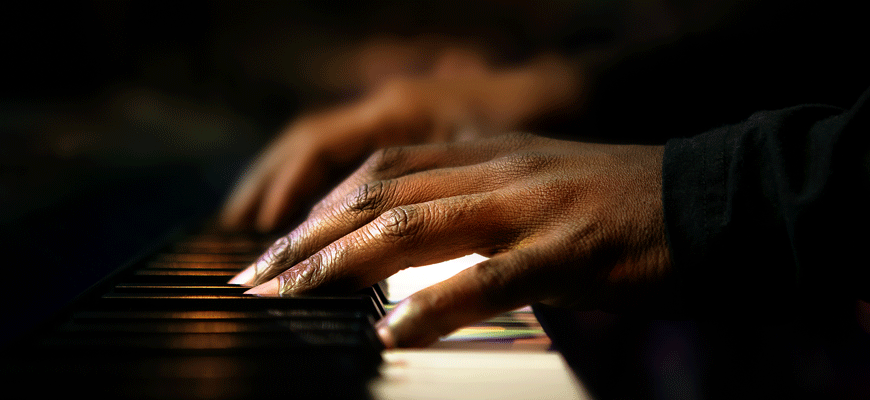foto ilustrativa de manos negras tocando un piano