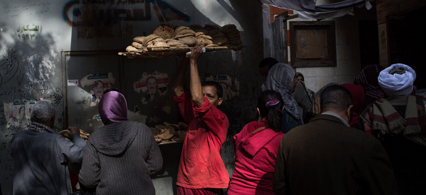 A man carries a tray of freshly baked bread outside a bread factory