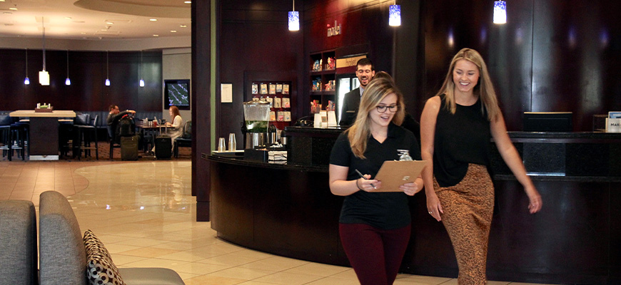 Students and alumni working at hotel, people dining in background