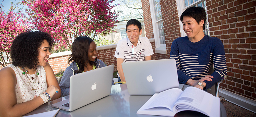 Three students smile while sitting at a table.