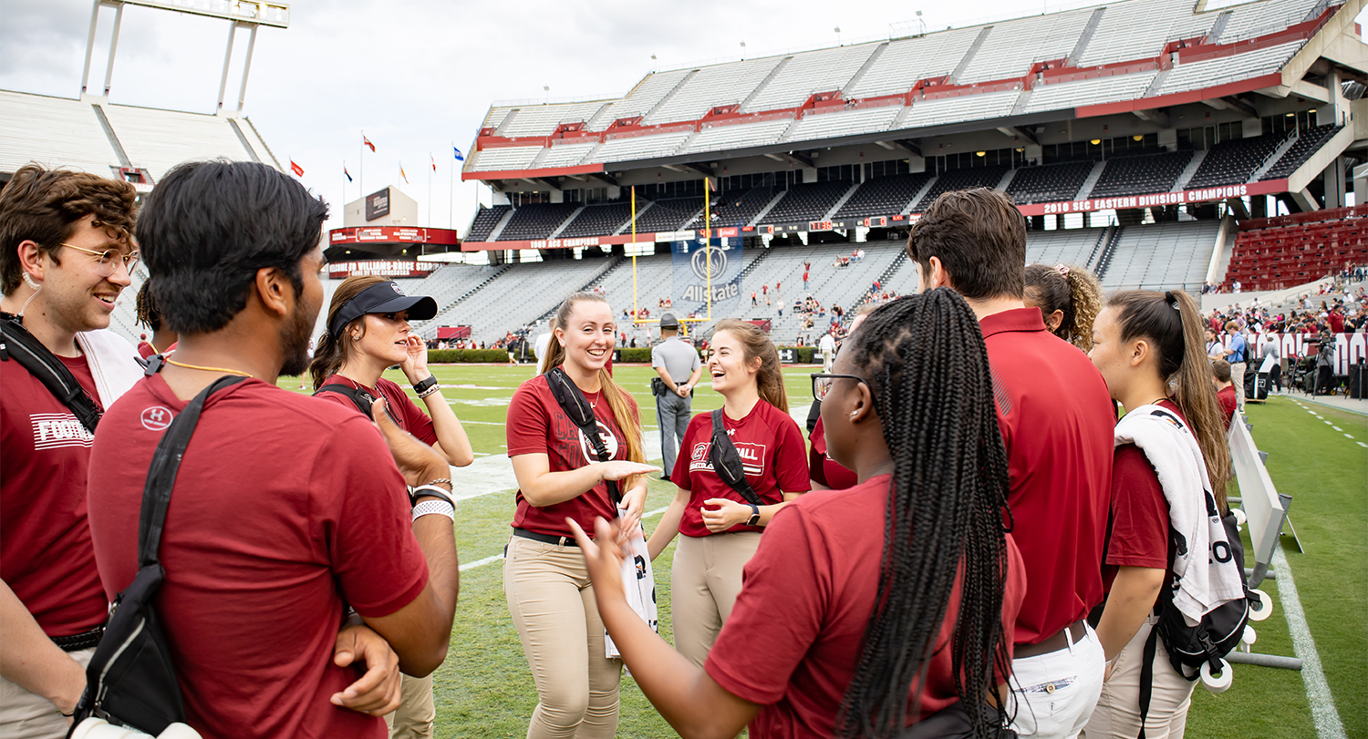 Student interns standing on the football field during the spring game.