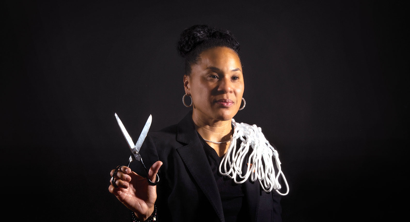 A studio portrait of Dawn Staley with net and scissors in hand.