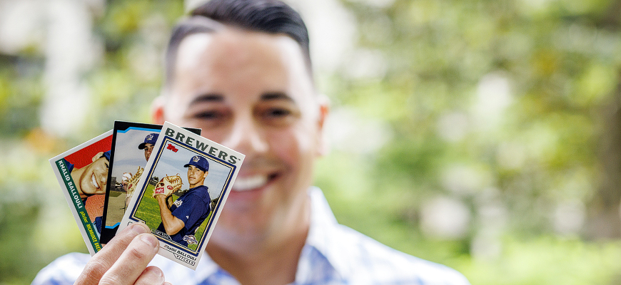 Khalid Ballouli holds baseball cards from his days as a player