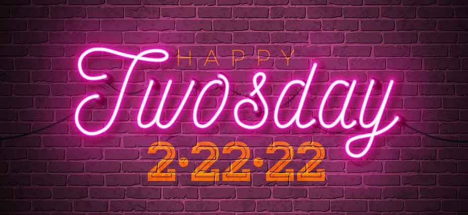 Neon signing a brick wall says happy twosday 2-22-22