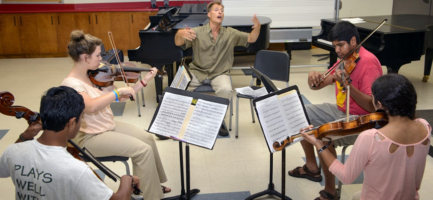 Students sit in a circle and play musical instruments