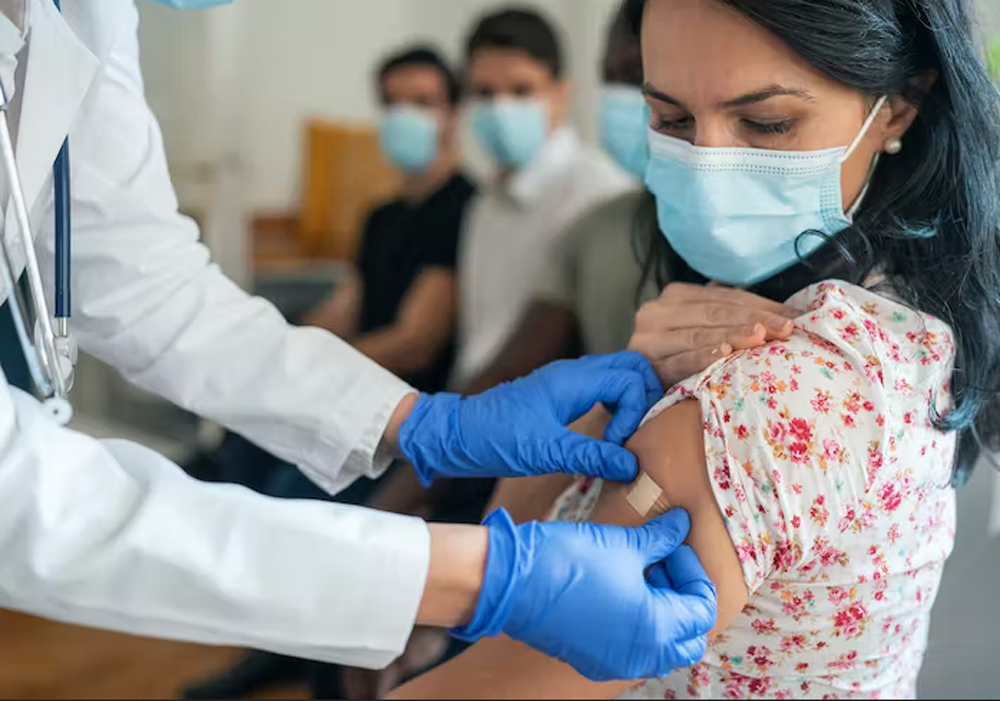 a health care worker puts a bandage on a woman's arm after giving her a shot