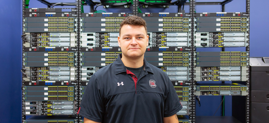 Man stands in front of a bank of computer servers