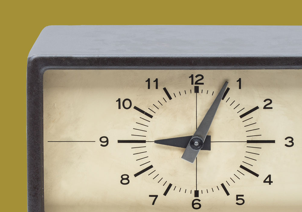A photograph of a time clock with a yellow ocre background.