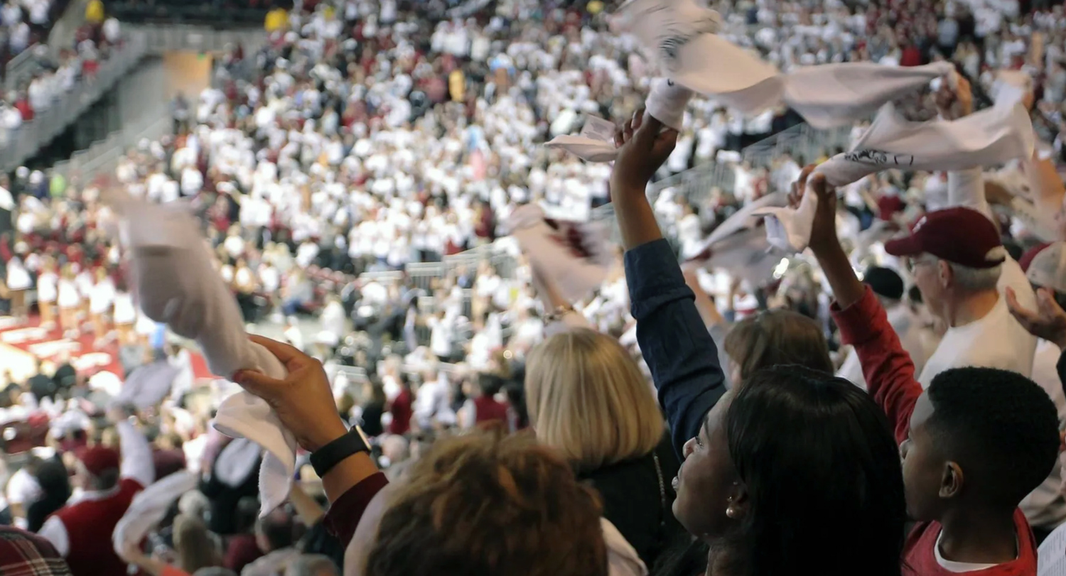 crowd waves white towels while cheering in an arean