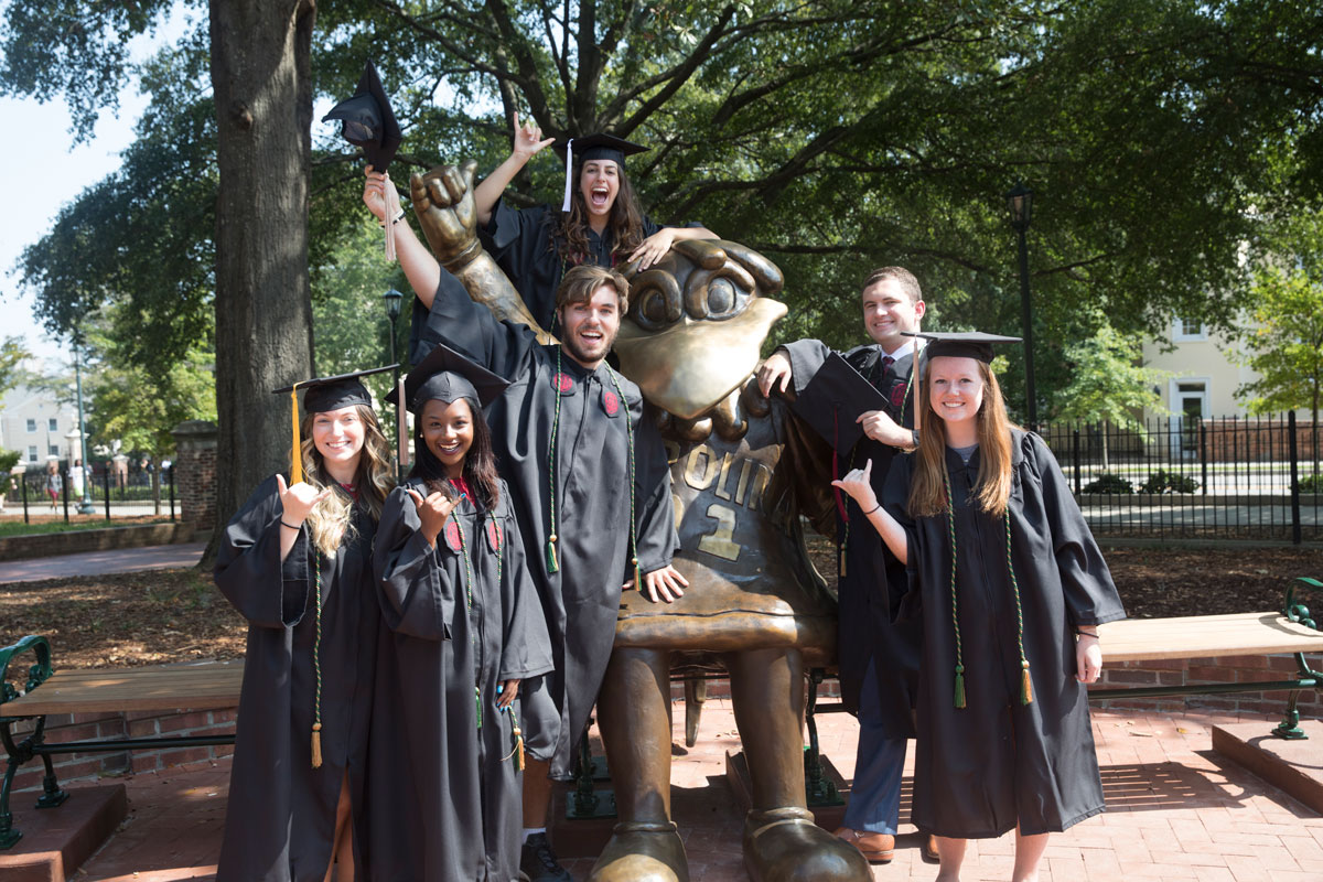 Graduates standing in front of a statue