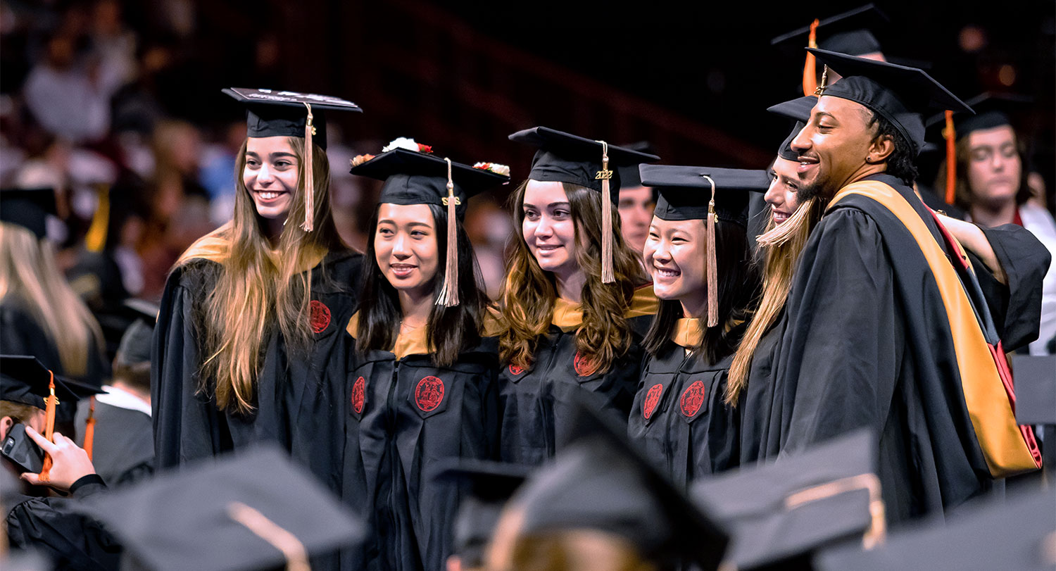 Group of students in their cap and gowns at a commencement ceremony.