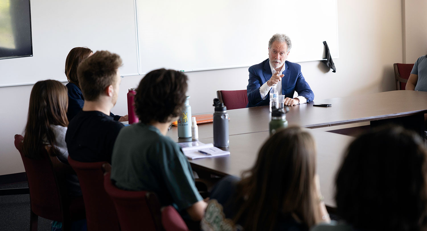 David Beasley speaks to students sitting around a rectangular table