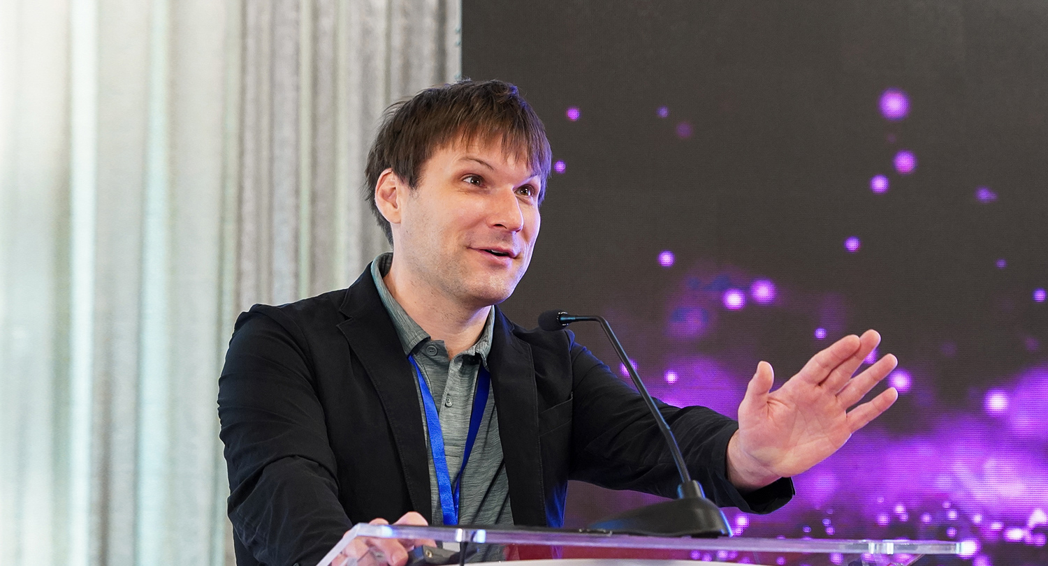 man speaks at a podium with a curtain in the background