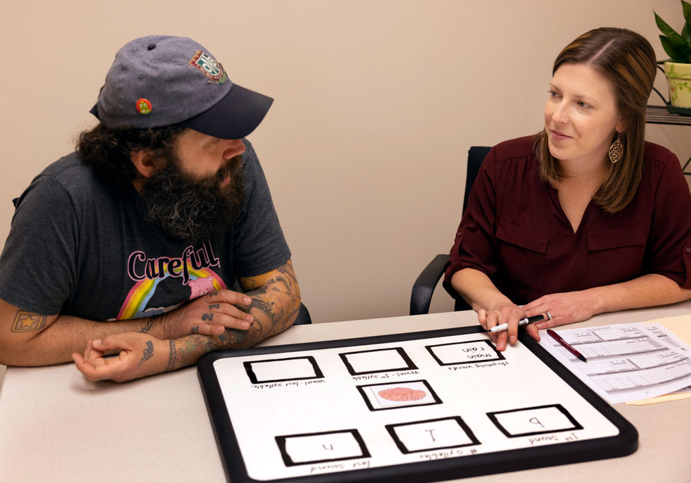 A patient and speech-language pathologist do a therapy activity at a table.