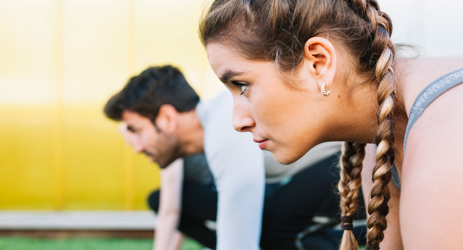 A photo of a female athlete with a male athlete in the background.