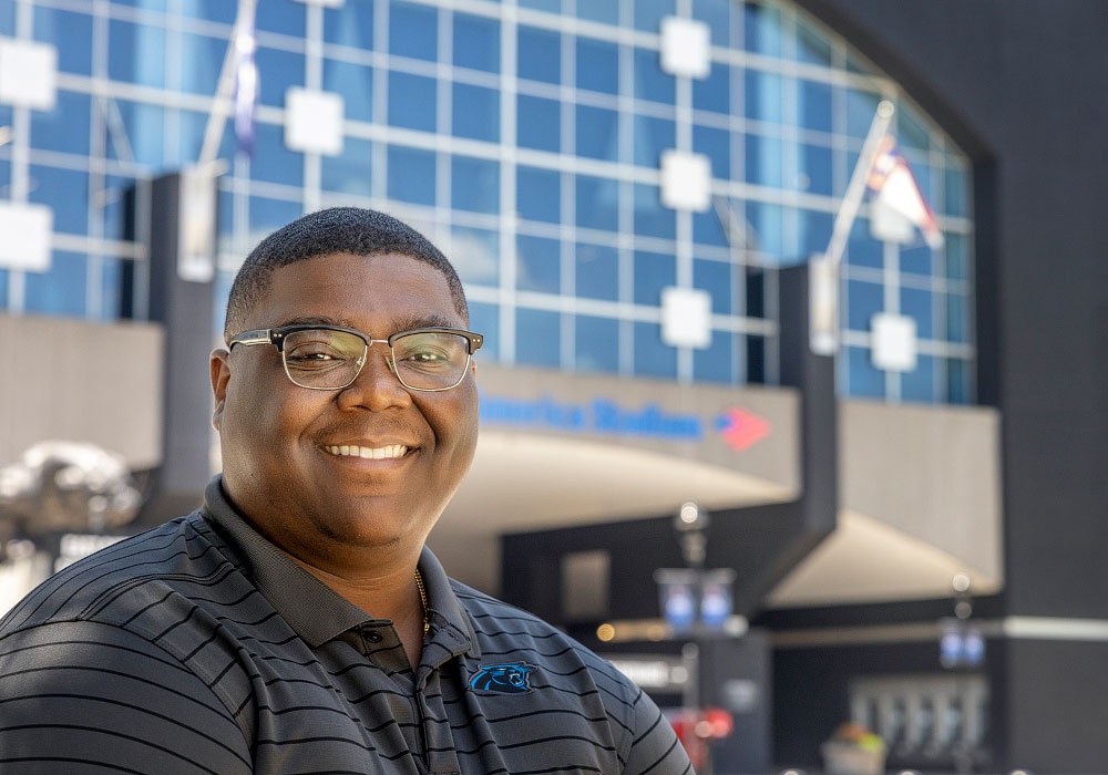 Alex Grant smiles outside Bank of America Stadium on a sunny day