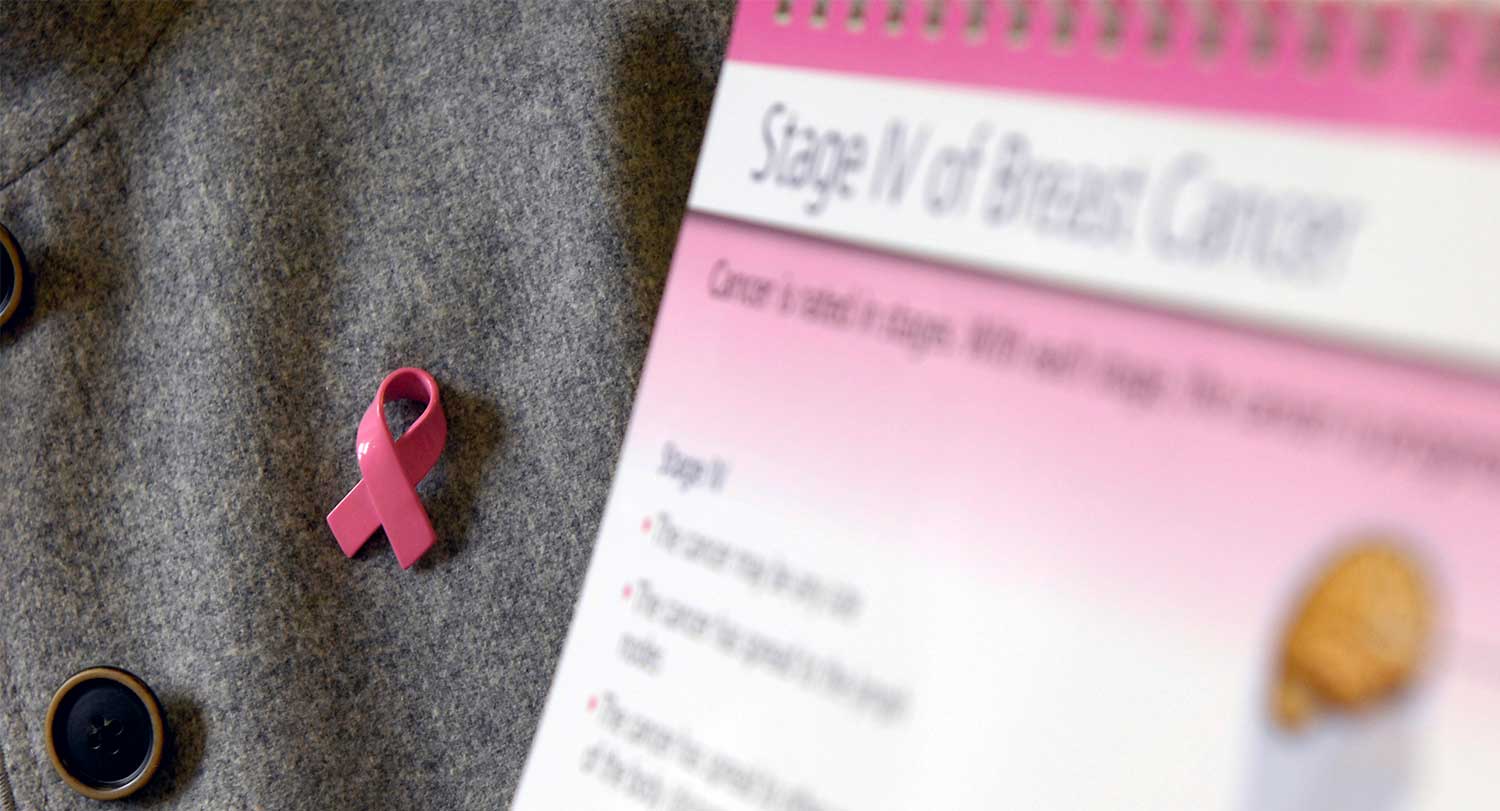pink ribbon lapel pin sits on a gray background