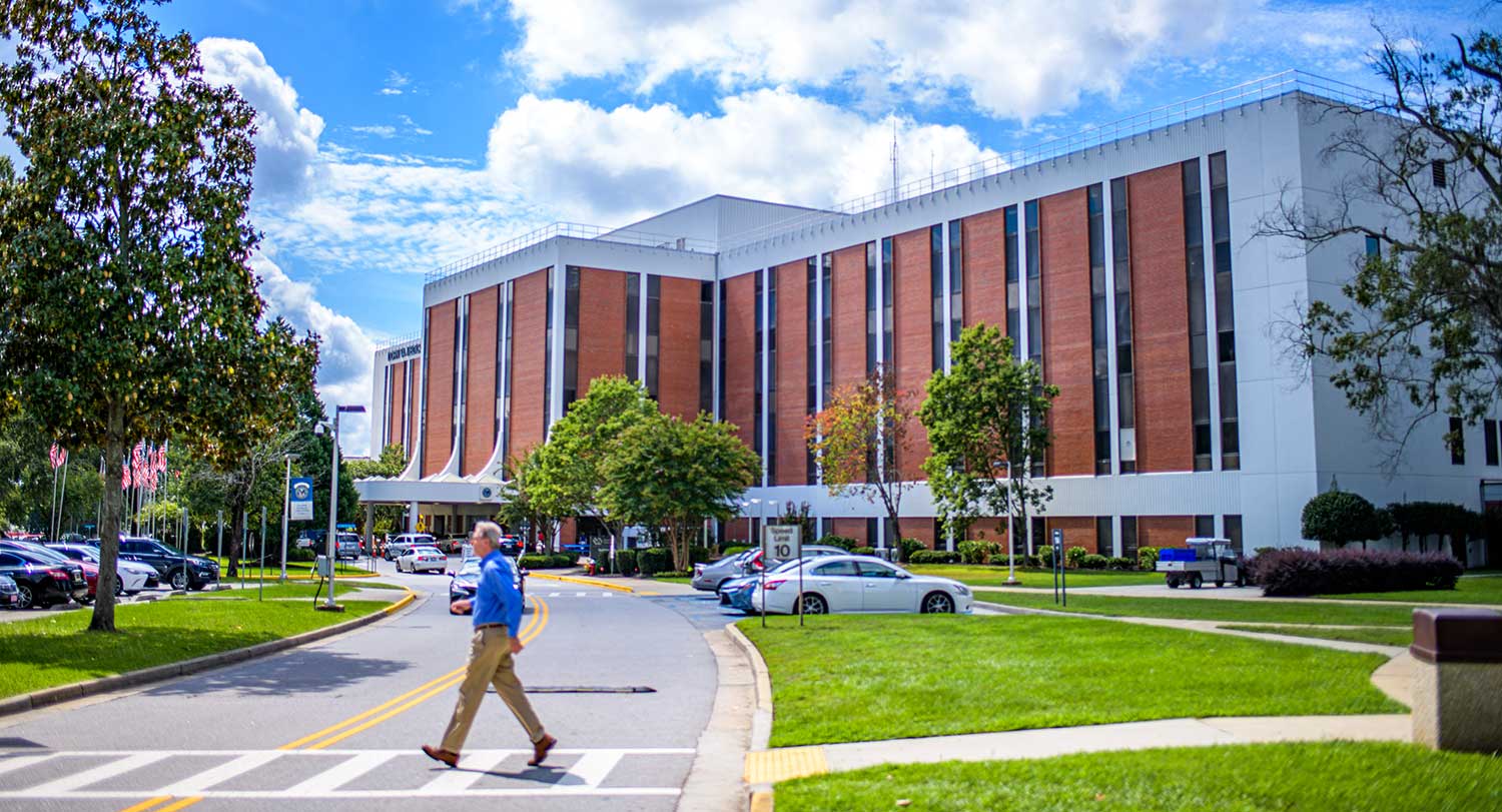 Man walks across VA hospital campus on a sunny day in Columbia, SC.