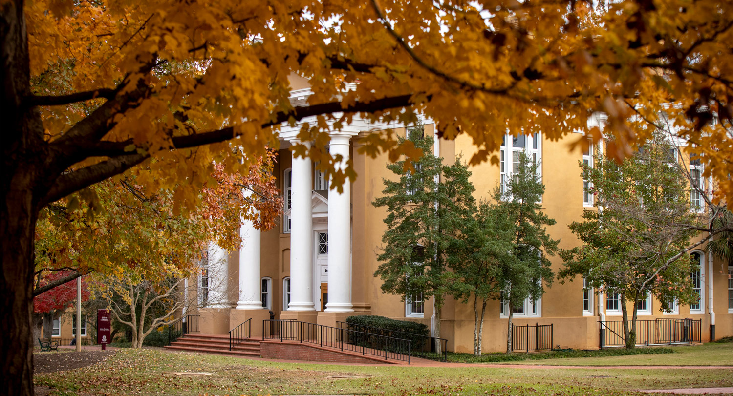 building with large white columns surrounded by fall foliage