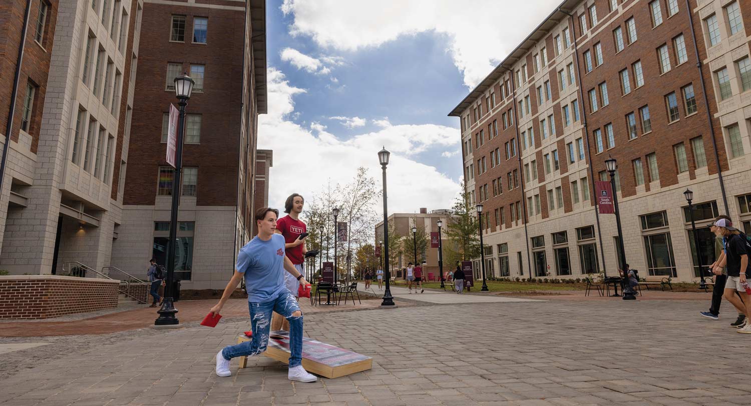 Students playing corn hole by Campus Village.