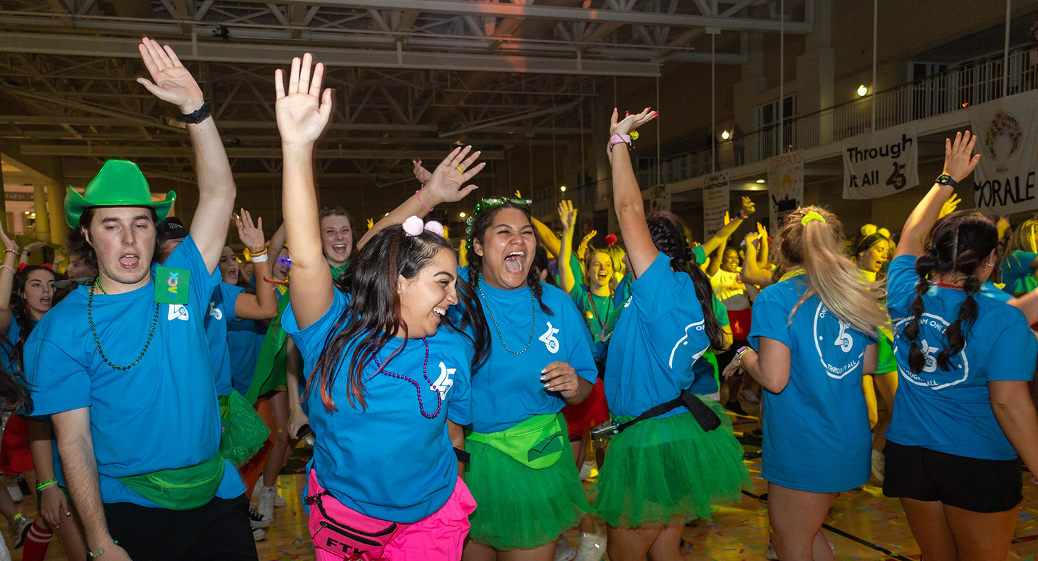Students with their hands in the air while they dance at USC's Dance Marathon