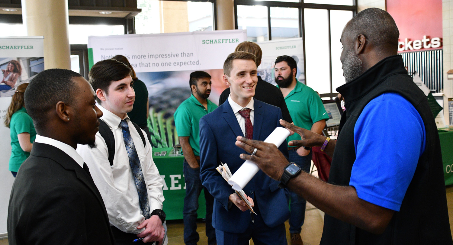 Three male USC students speak to business representative at the STEM Job Fair.