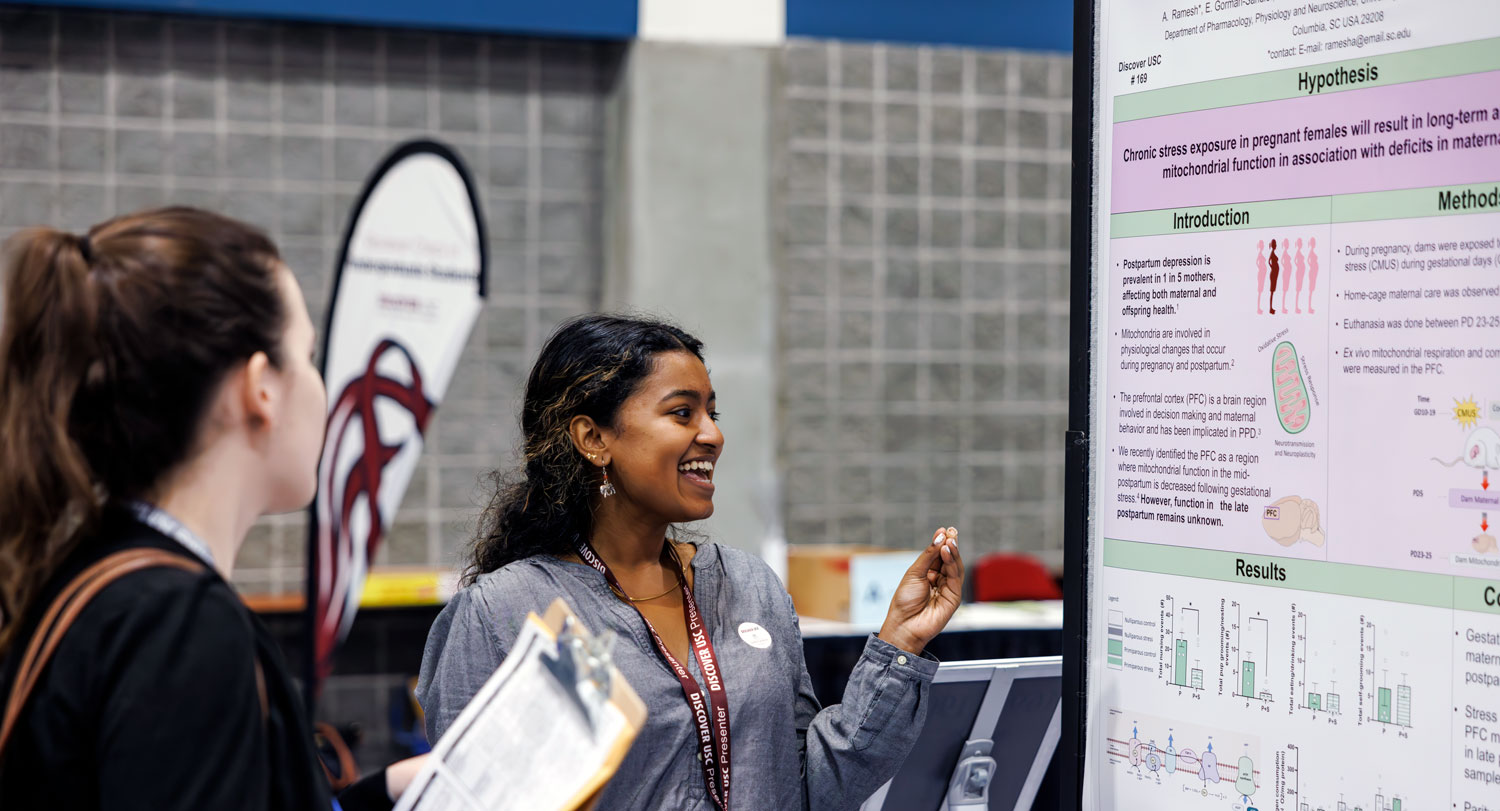 two women talk and look at research posters