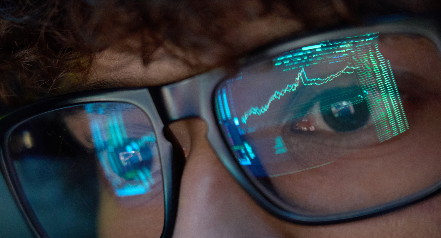 Data from a computer screen is reflected in the eyeglasses of a researcher.