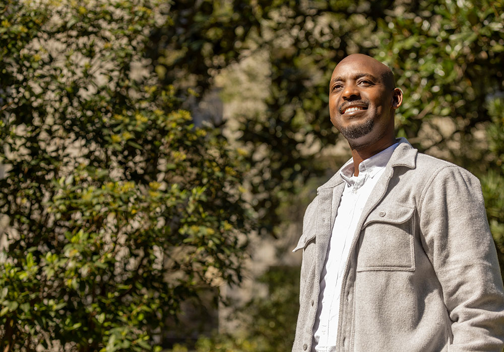 A photo of Aaron Gaga standing outside and looking away from the camera.