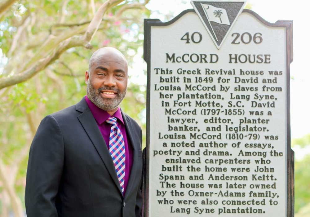 Jackie Whitmore stands next to a historical marker in South Carolina.