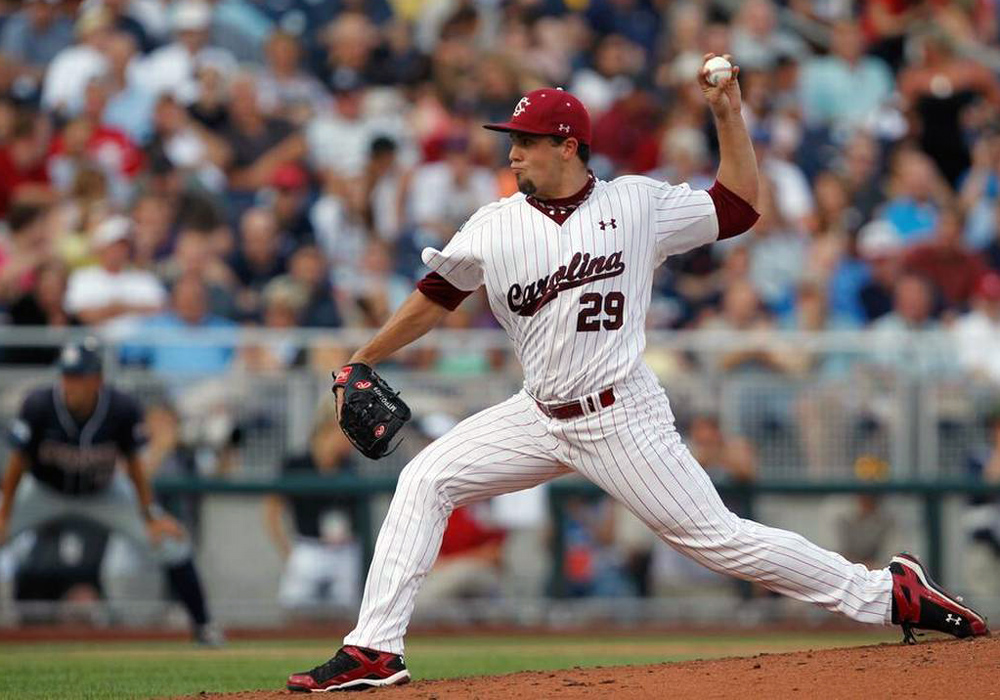 baseball pitcher wearing a Carolina Gamecocks uniform in full throw motion from the mound