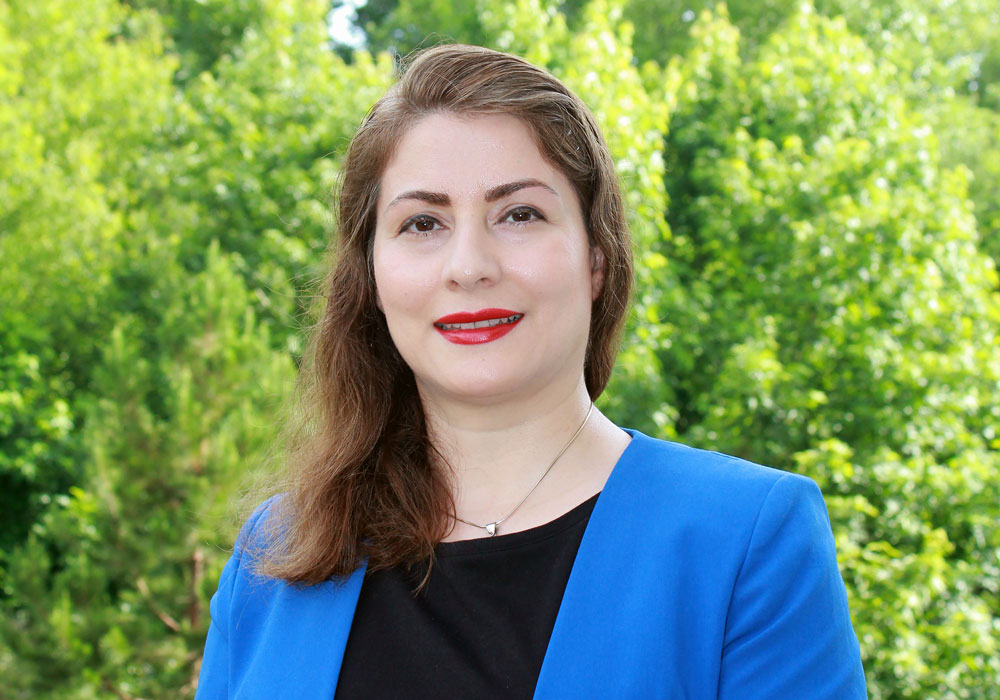 woman stands out side in front of greenery