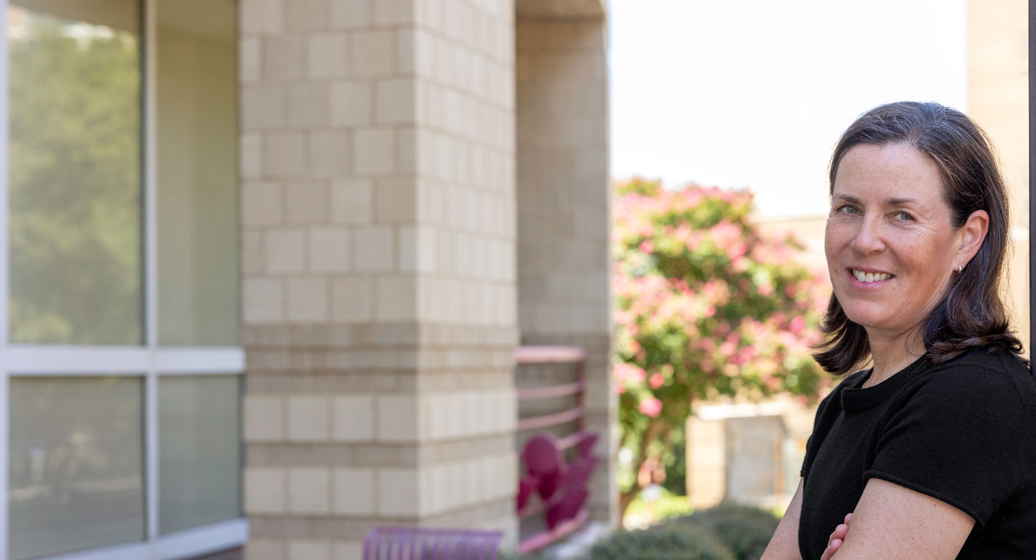 woman stands outside leaning against a building