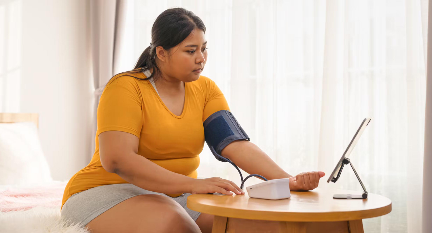 Young woman checks her blood pressure with a monitoring cuff.