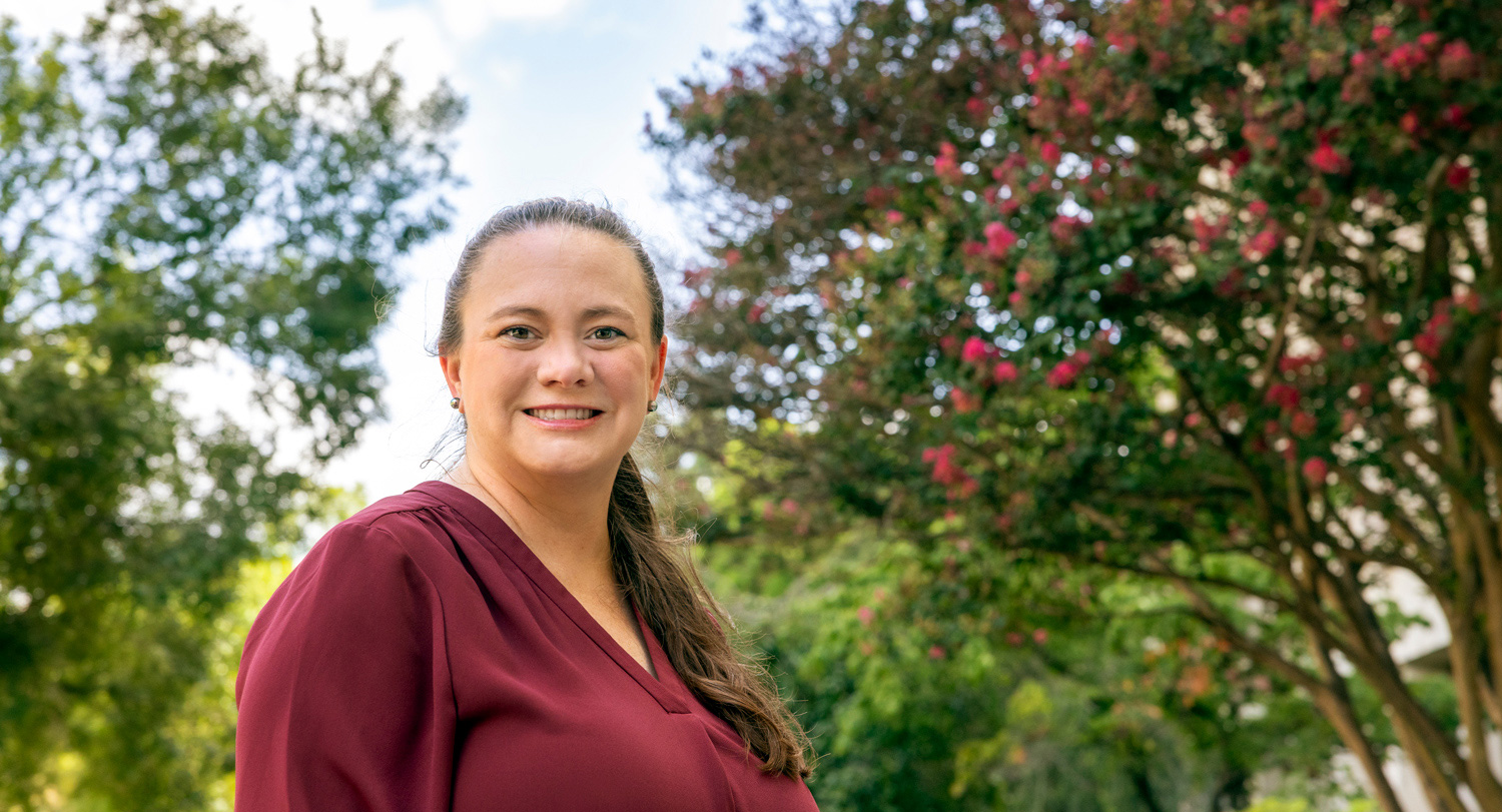 woman stands outside with trees in the background