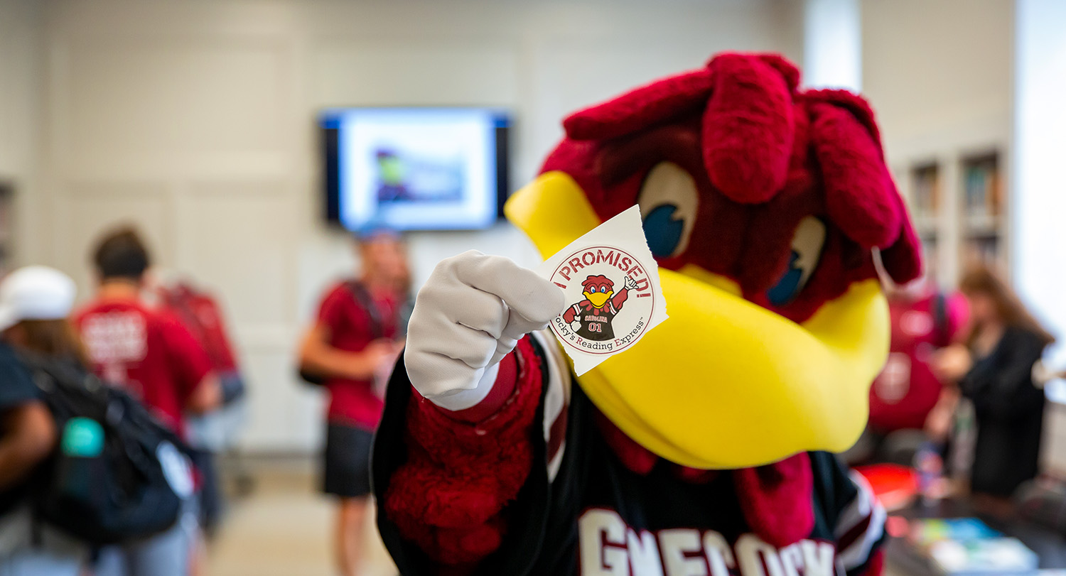 Cocky holds up sticker reading, "I promise"