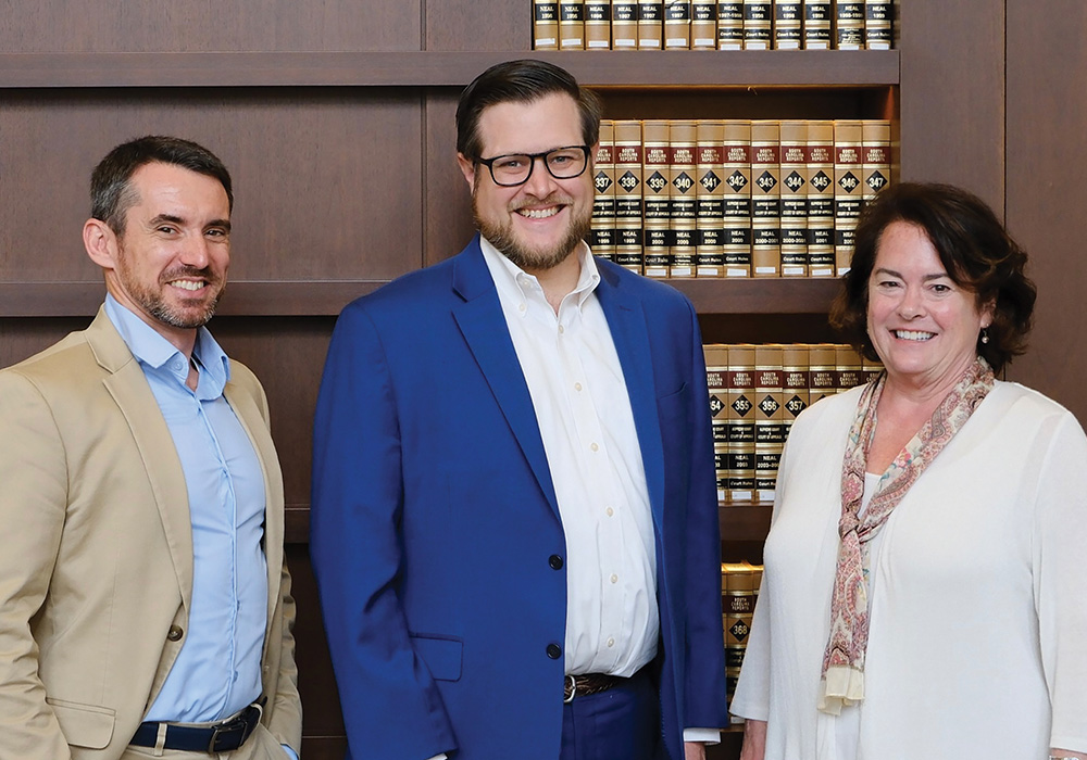 Three faculty members in front of a bookcase