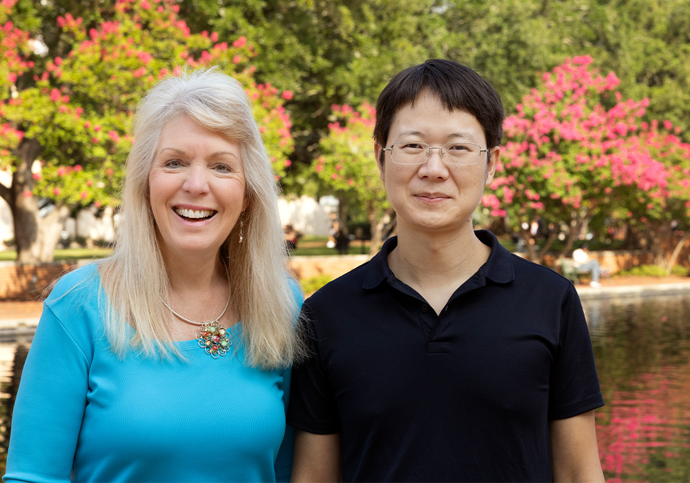 Susan Richardson and Jiafu Li pose by the reflection pool outside Thomas Cooper Library