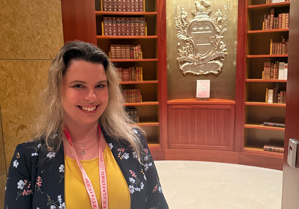 woman stands in front of library shelves with books